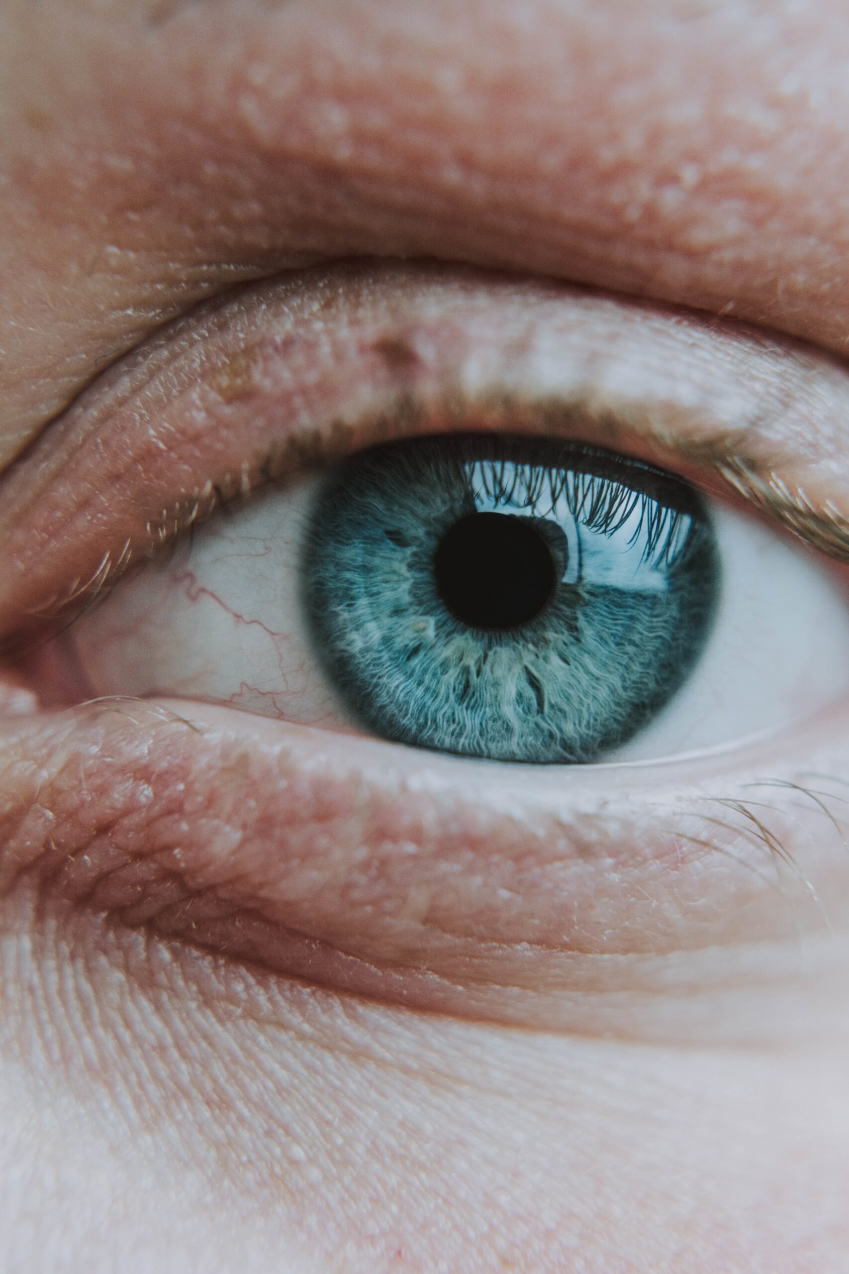 A vertical closeup shot of an elderly human's light blue eye
