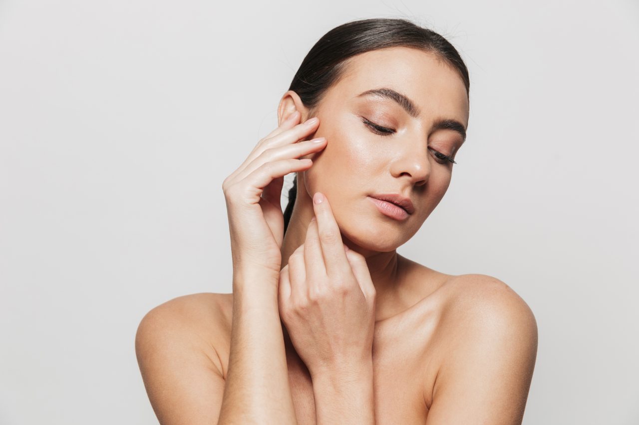 Beauty portrait of a pretty young topless woman standing isolated over white background