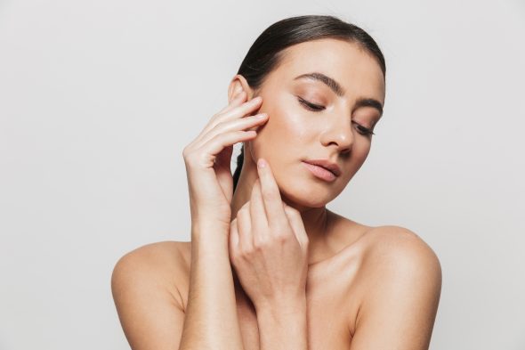 Beauty portrait of a pretty young topless woman standing isolated over white background