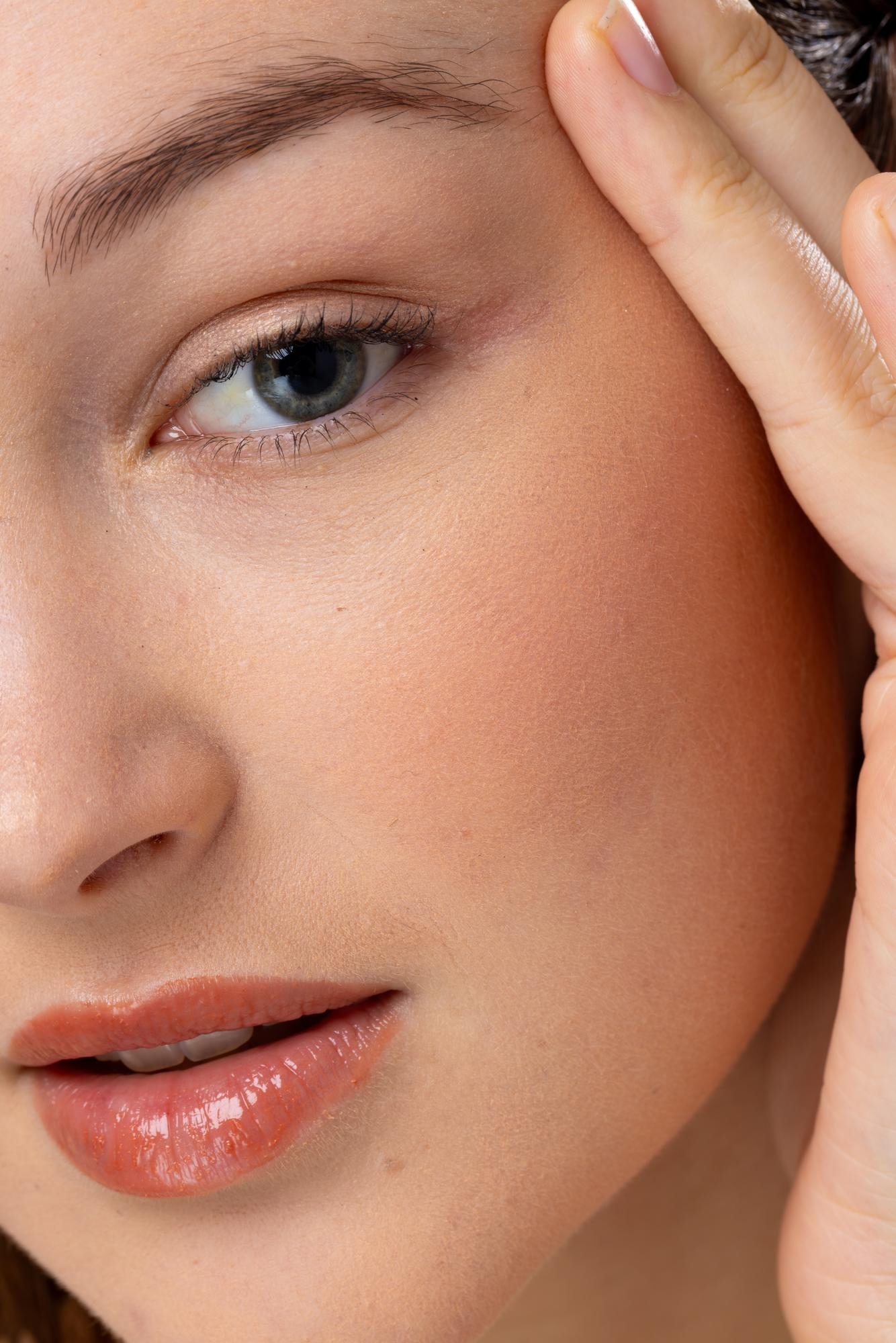 Close-up of a woman’s eye and cheek area highlighting natural skin texture, eyebrow shape, and minimal makeup.