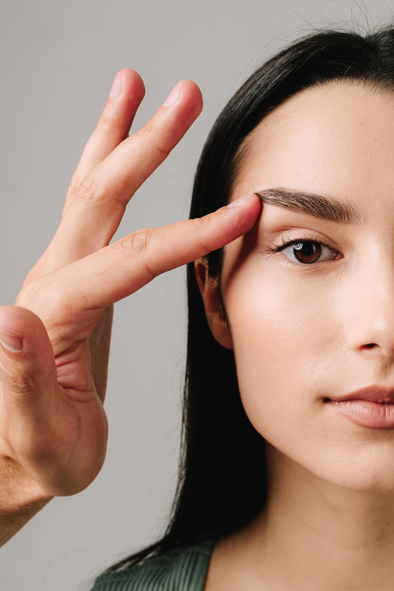 Woman with eyes closed resting her hand on her shoulder, conveying calmness and skin wellness.