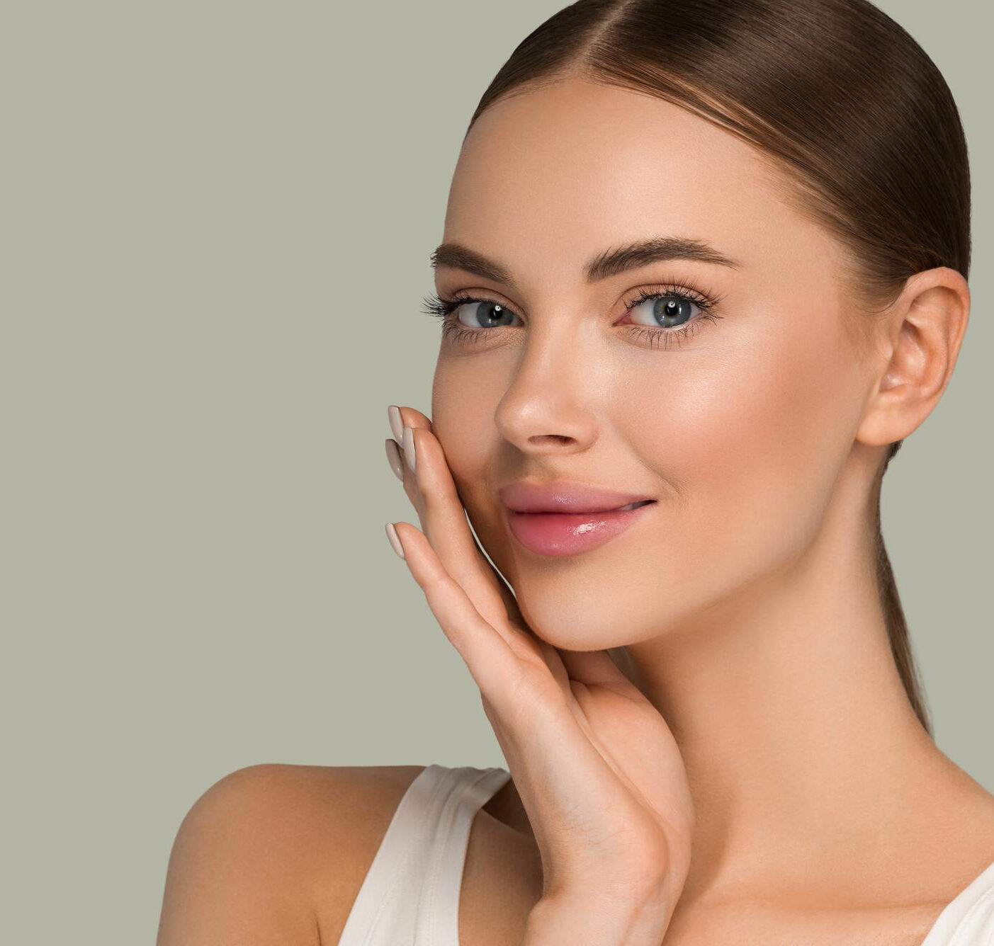 Portrait of a woman with smooth, radiant skin gently touching her face and smiling slightly.