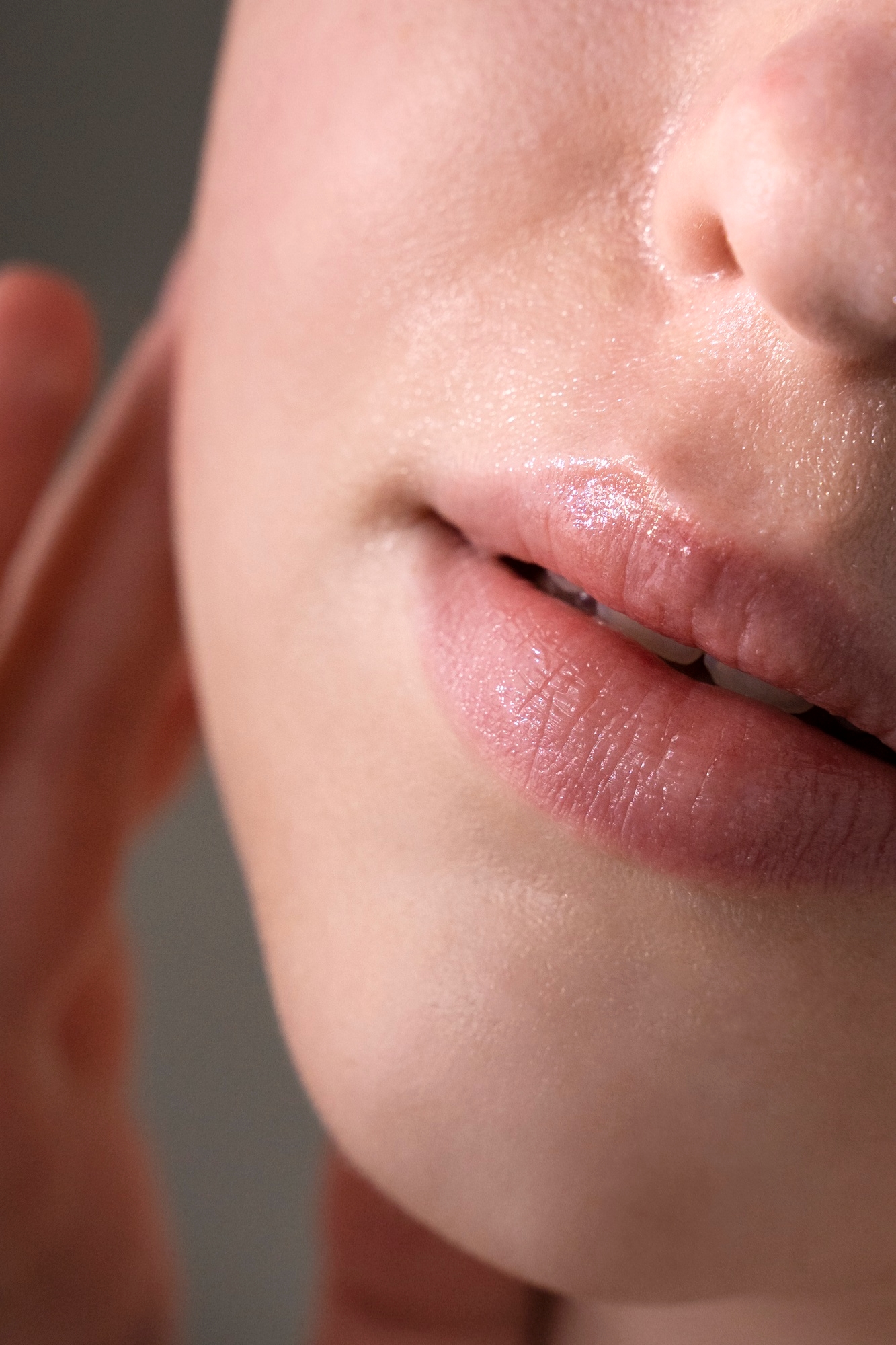 Extreme close-up of hydrated lips and lower face with dewy skin texture and soft natural lighting.