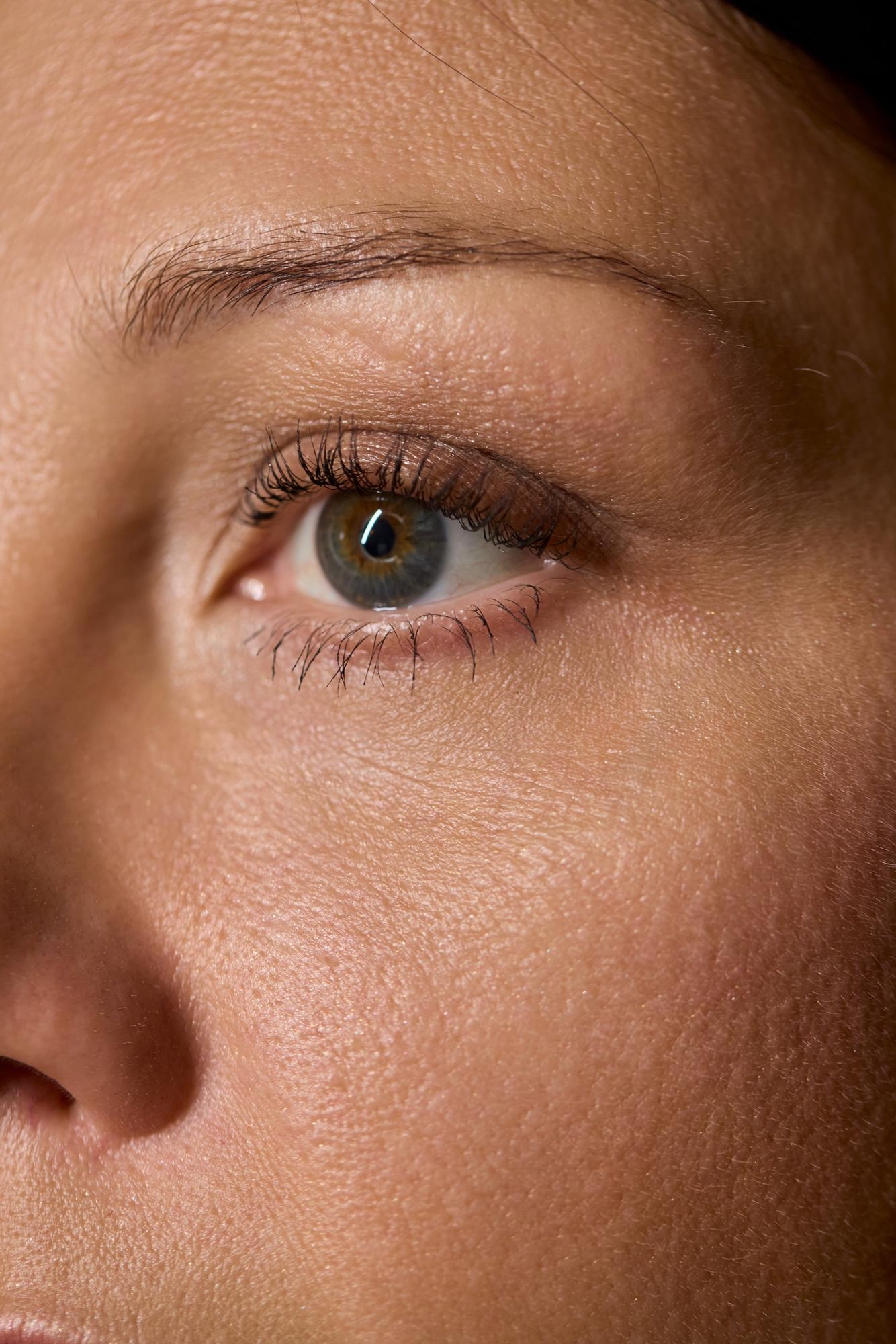Extreme close-up of a woman’s eye and eyebrow showing natural skin texture