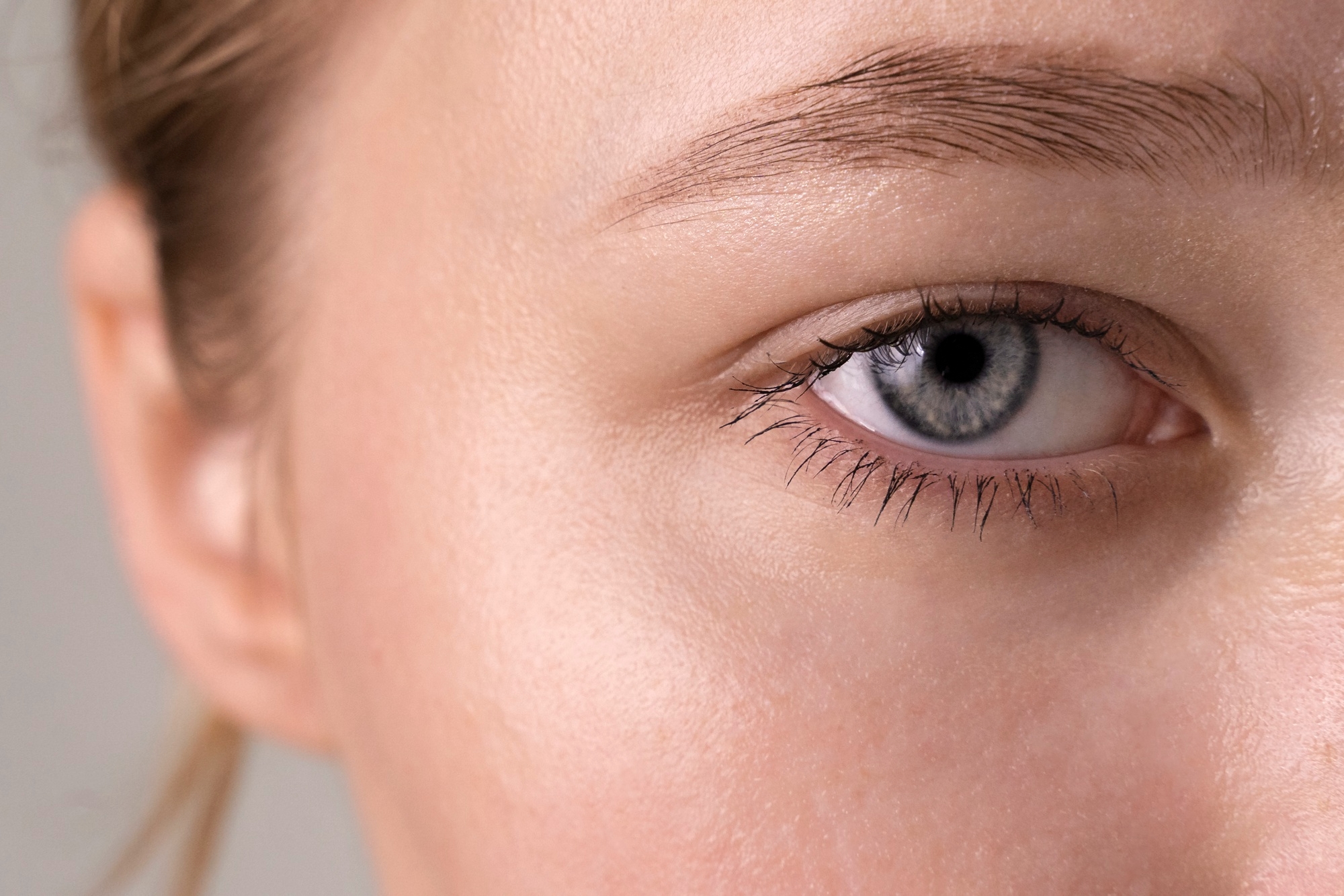 Close-up of a blue eye, eyebrow, and natural skin texture.