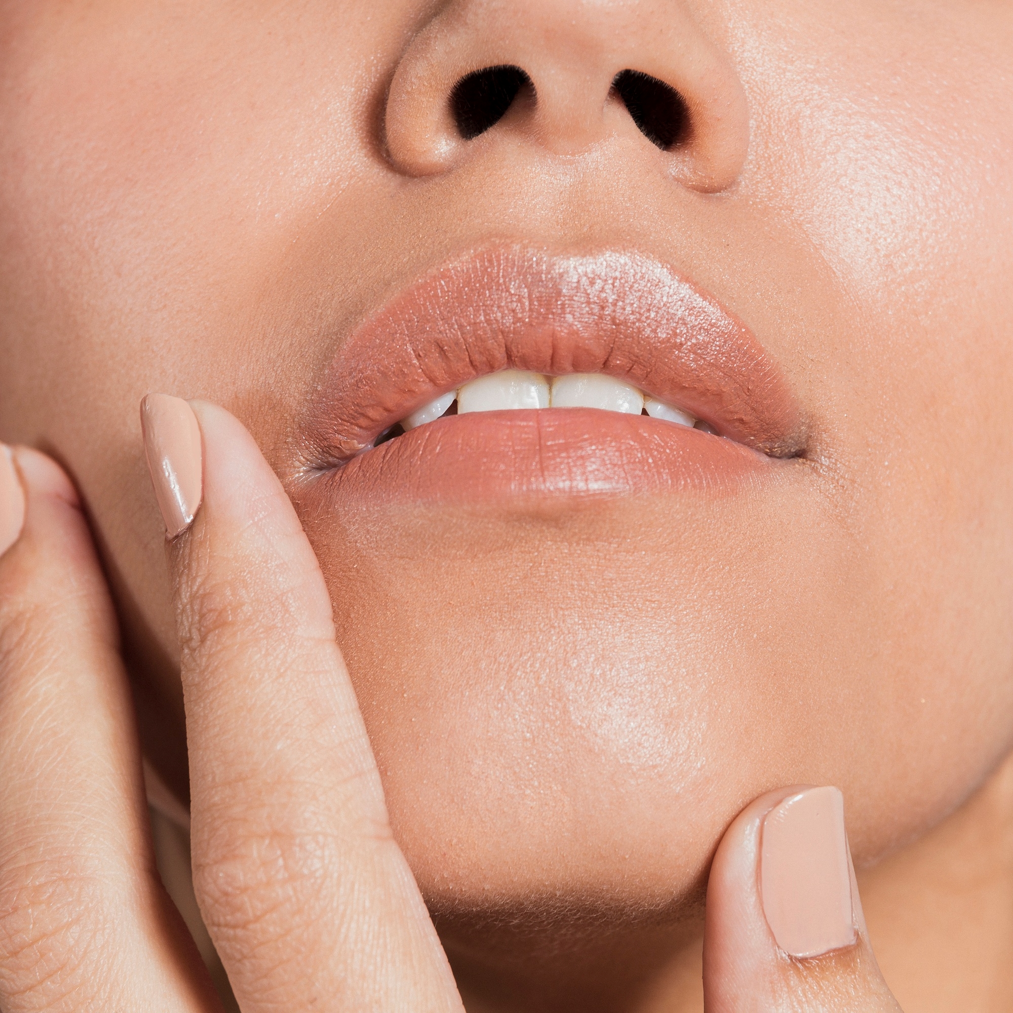 Extreme close-up of glossy natural lips with fingertips near the face.