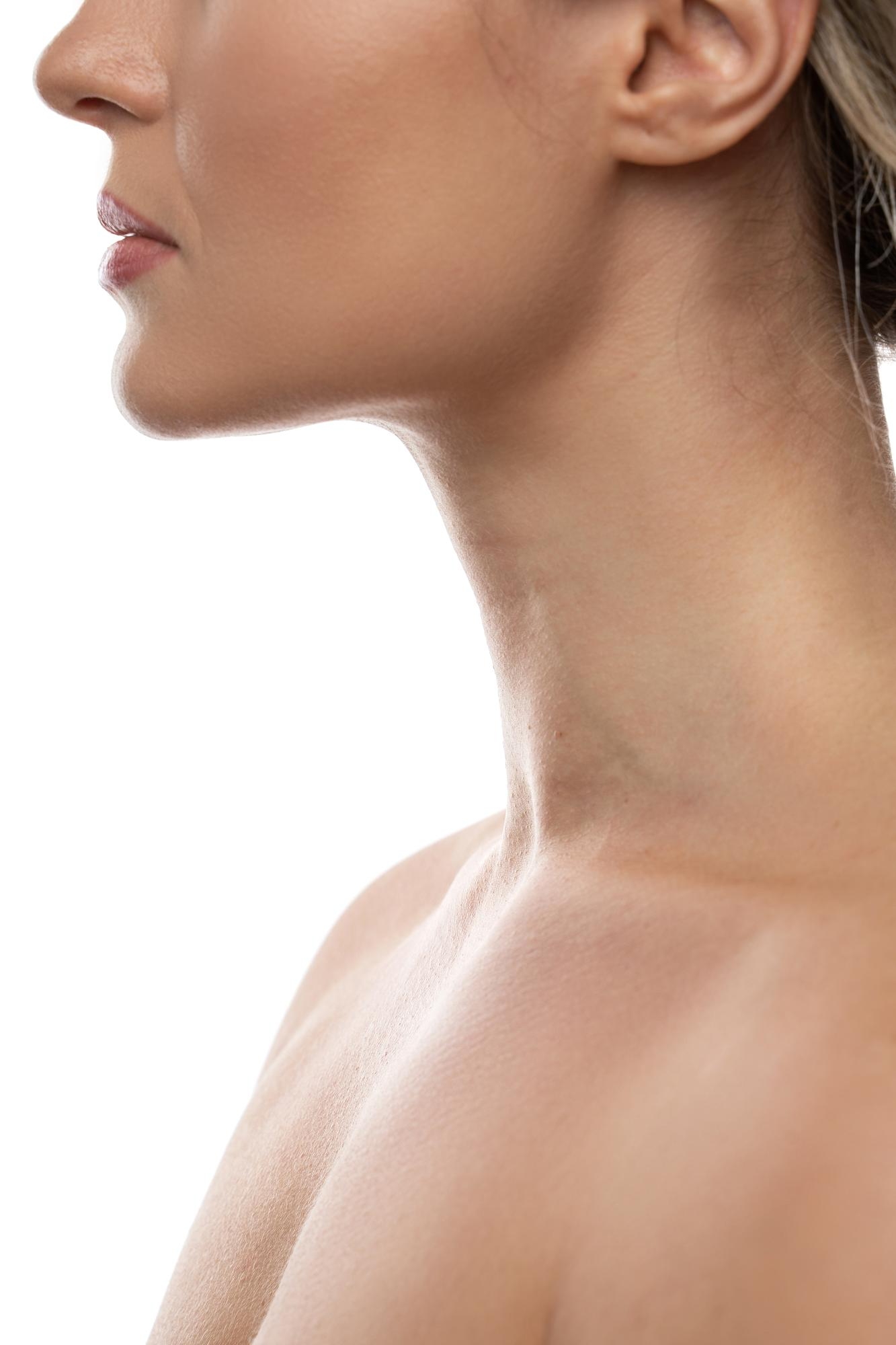 Close-up side profile of a woman’s jawline, neck, and shoulder on a white background.