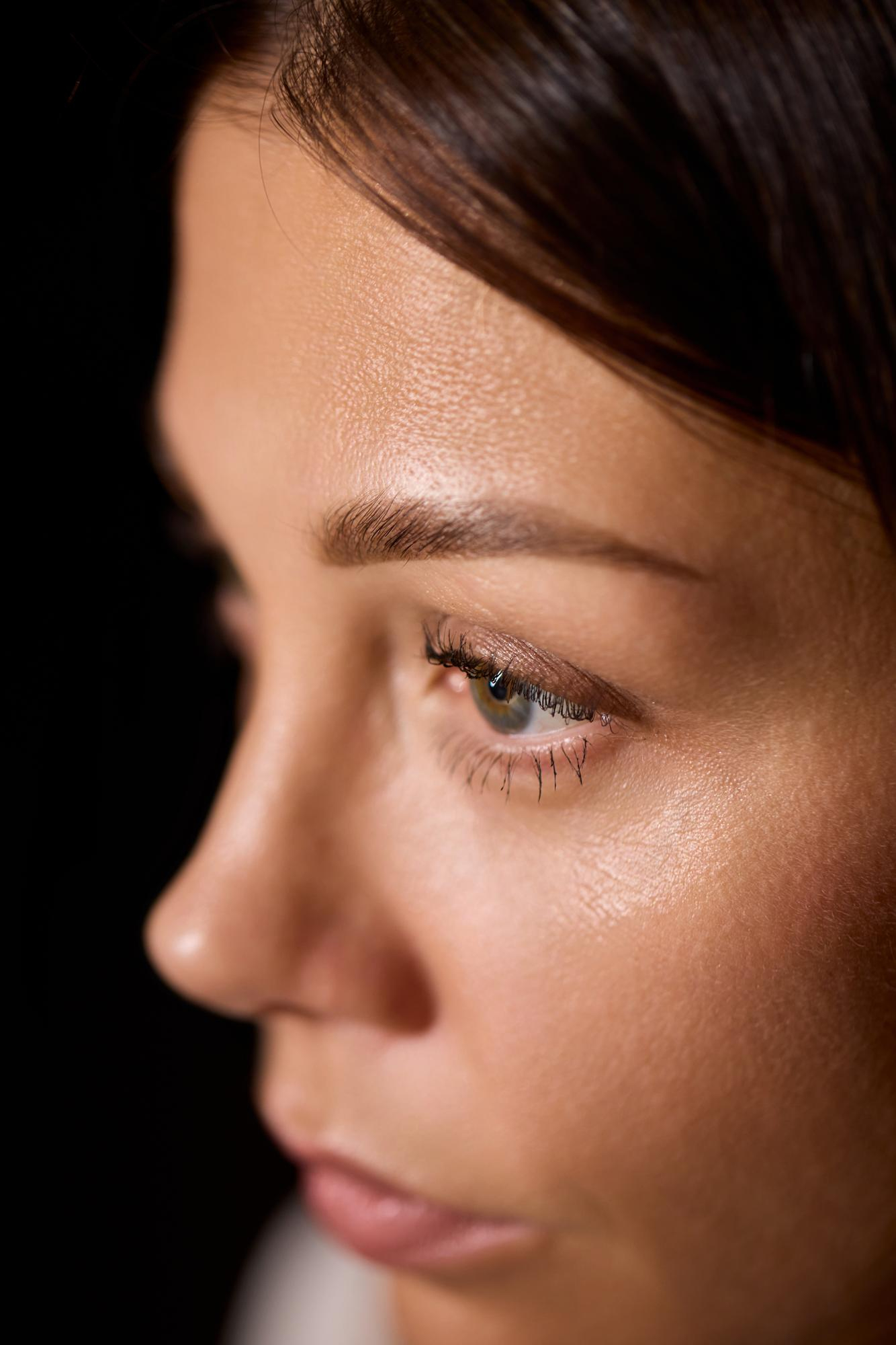 Side-profile close-up of a woman’s eye and dewy skin texture.