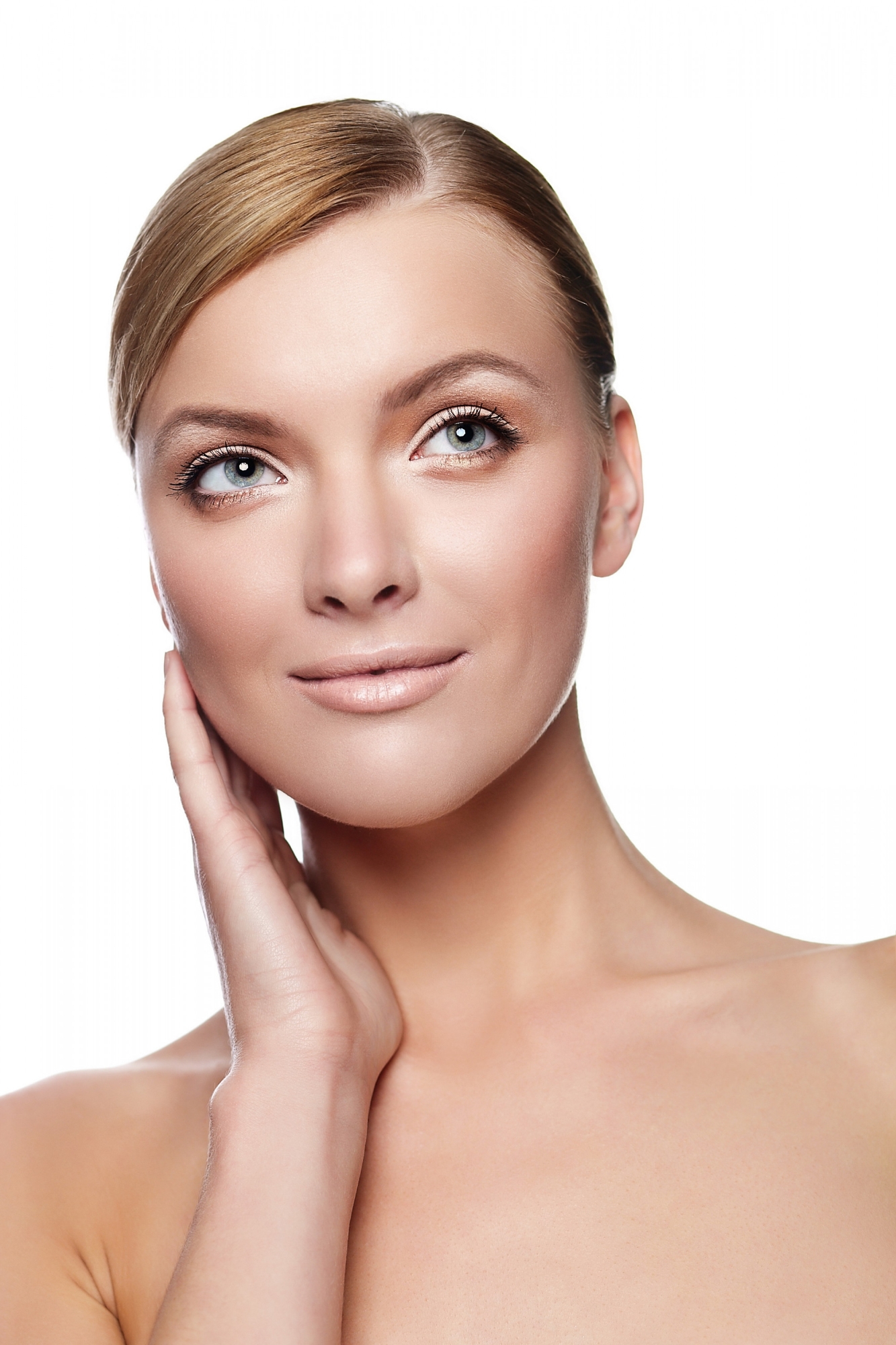 Beauty portrait of a blonde woman with smooth skin touching her neck and looking upward against a white background