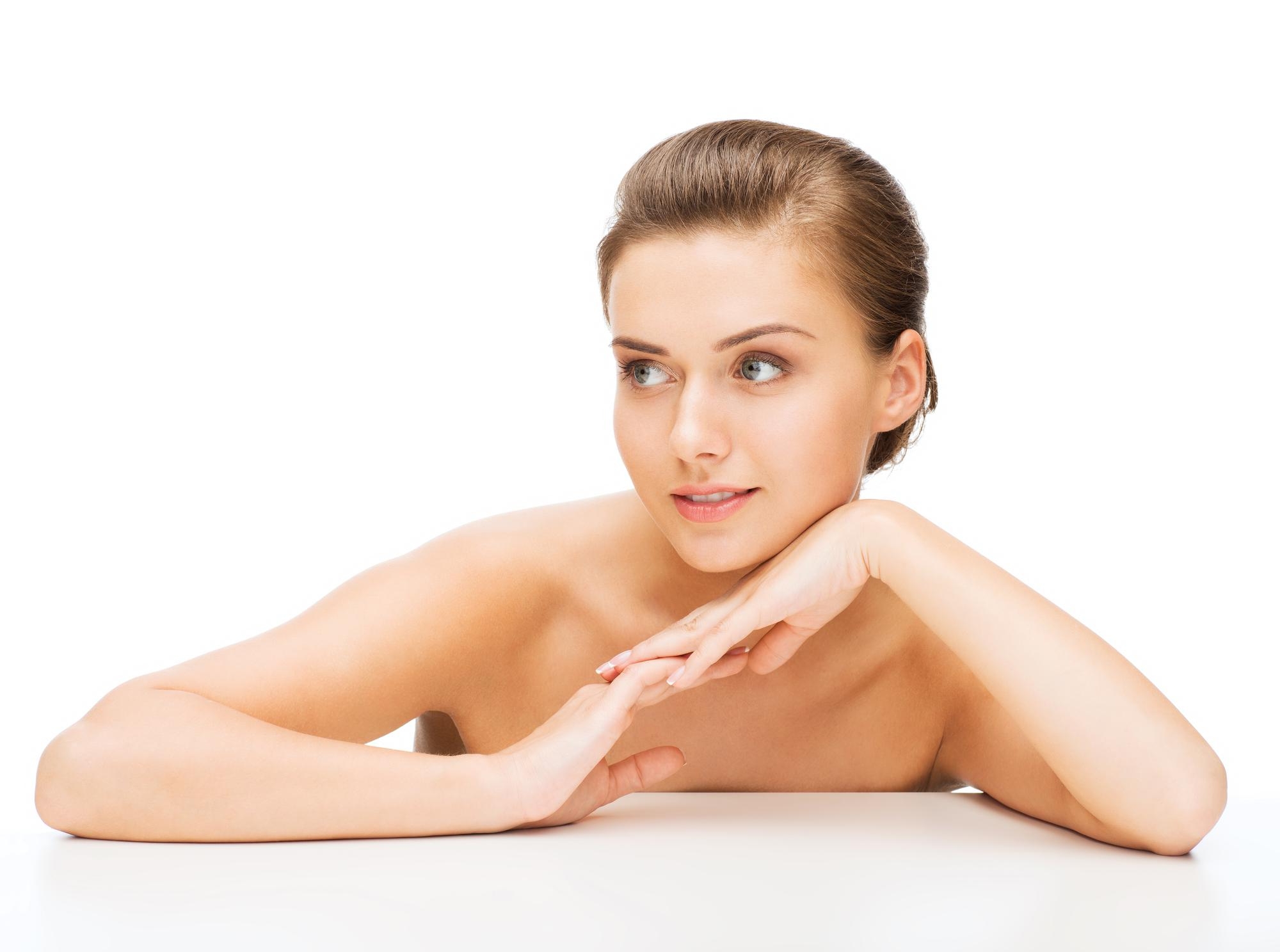Beauty portrait of a woman with smooth skin resting her chin on her crossed arms against a white background