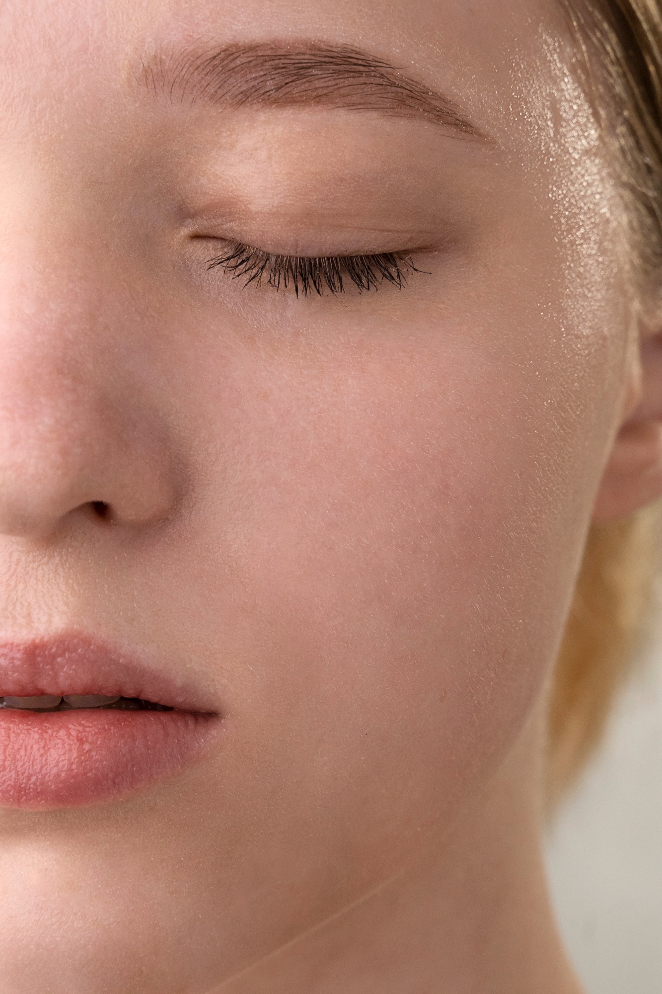 Close-up of a woman's closed eye and cheek showing smooth, glowing skin