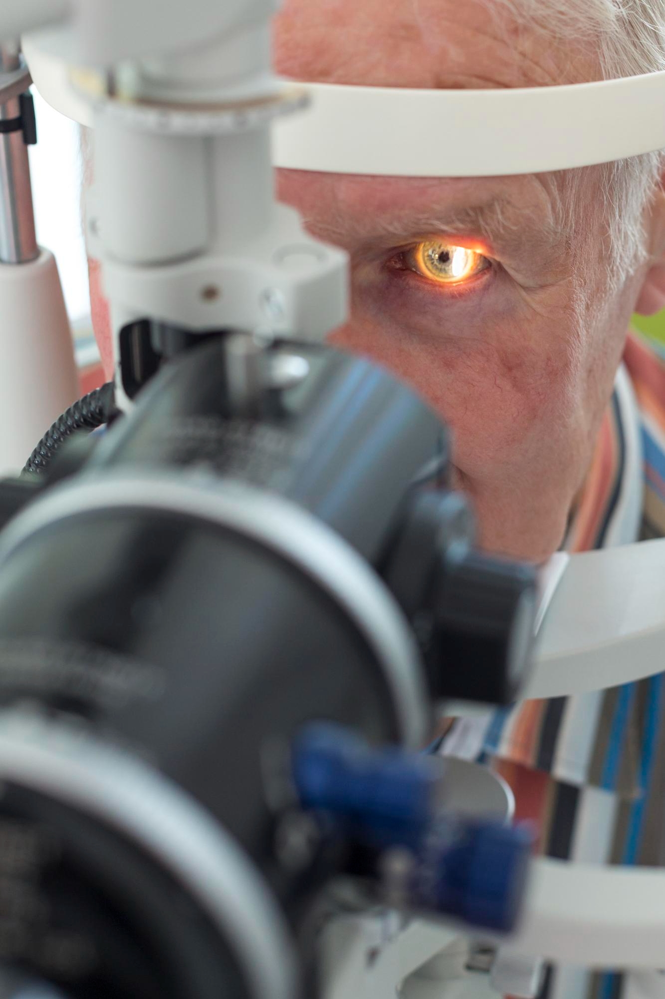 Elderly man having his eye examined with a slit lamp during an ophthalmology eye test