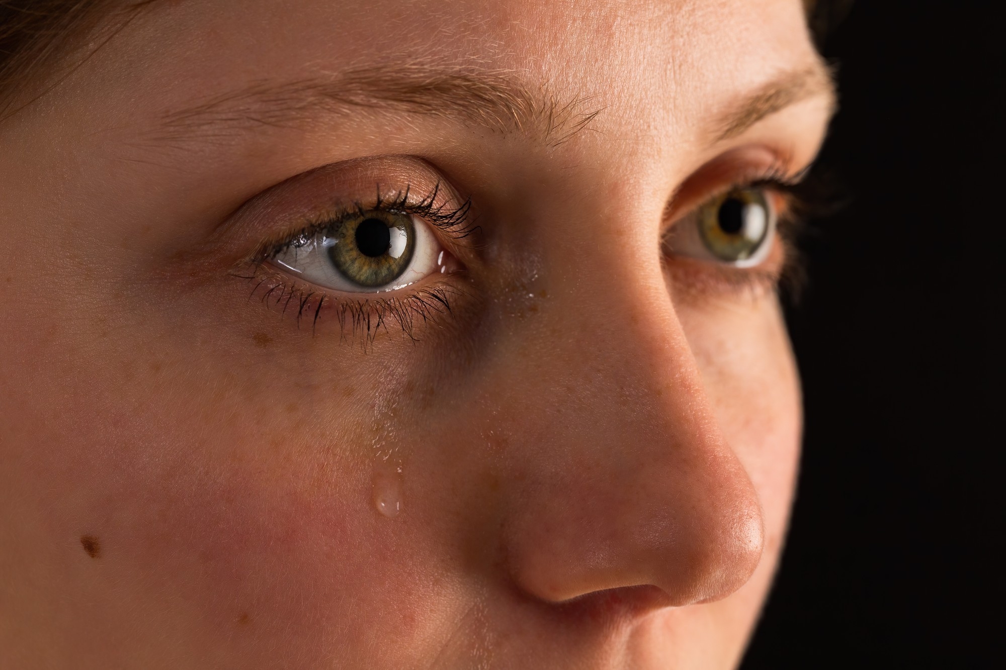 Close-up of a woman's face with a tear rolling down her cheek