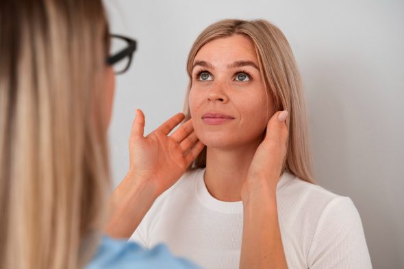 Practitioner assessing the face of a blonde woman during a skin consultation at a clinic