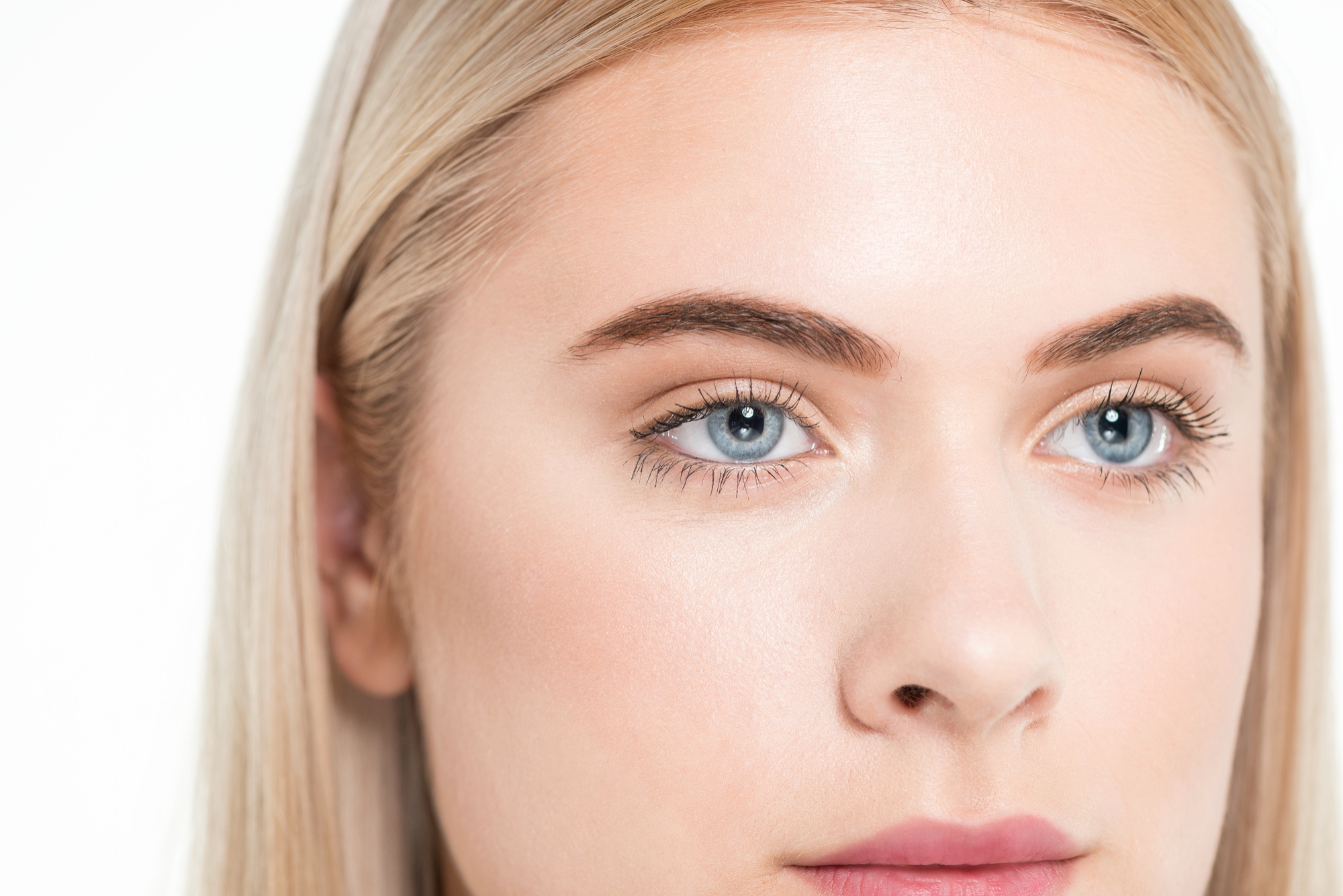 Close-up of a young blonde woman's face with bright blue eyes and defined eyebrows